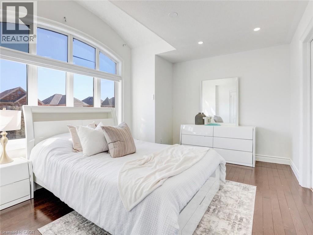 Expansive arched window with multiple panes, recessed lighting, white walls, dark wood-finish flooring, and white trim throughout - 584 Pinery Trail, Waterloo, ON - Indoor Photo Showing Bedroom