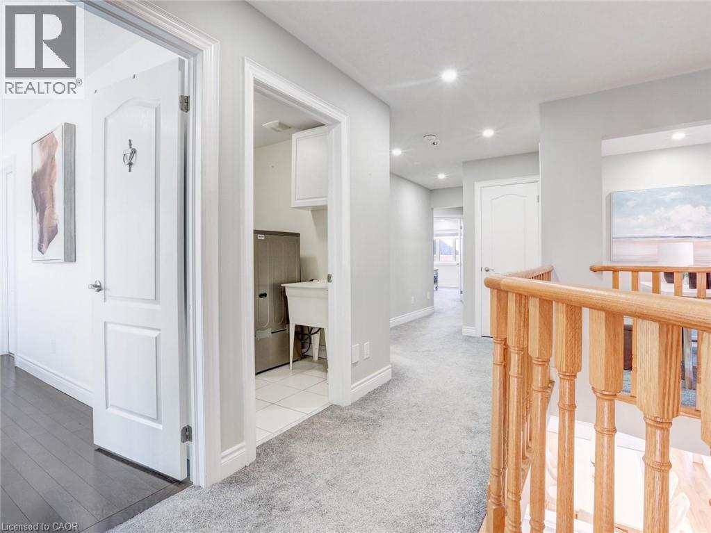 Hallway featuring light gray carpet, recessed lighting, white trim, and a natural wood staircase railing - 584 Pinery Trail, Waterloo, ON - Indoor Photo Showing Other Room