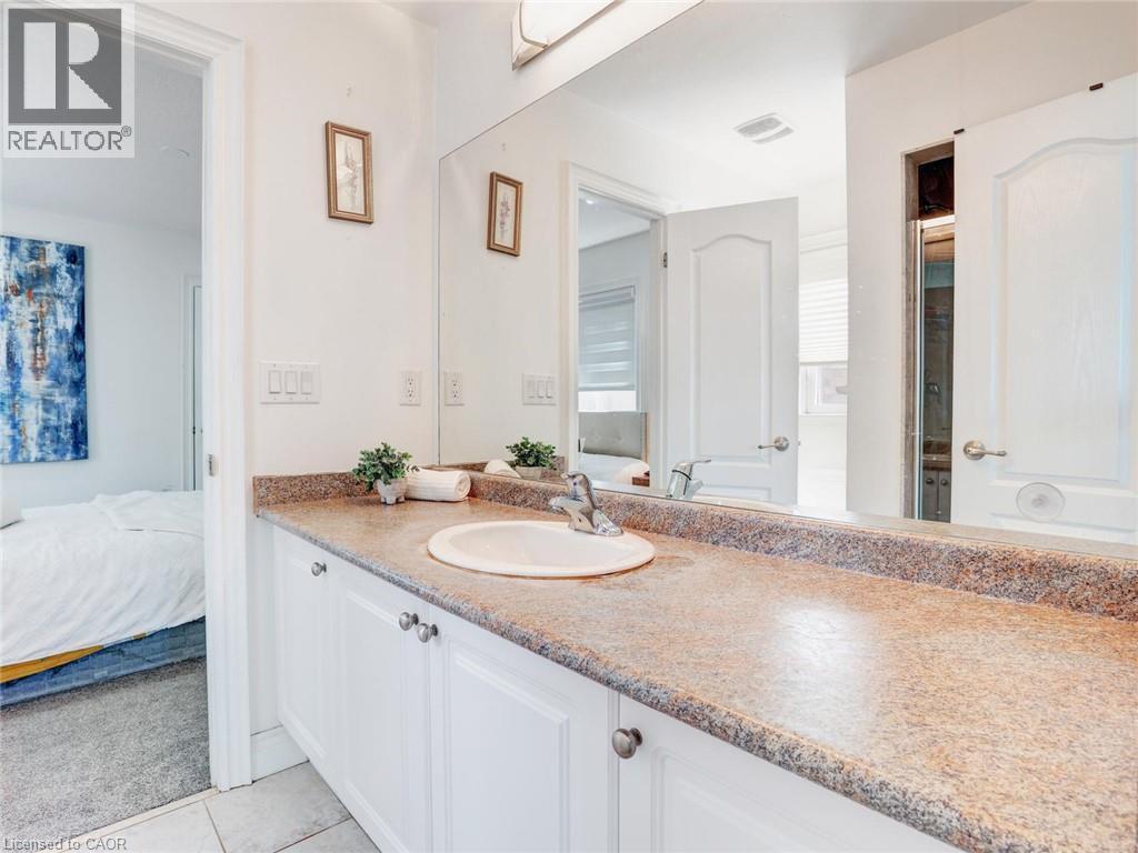 Bathroom vanity featuring a speckled countertop, integrated sink, and white cabinetry with silver-toned hardware - 584 Pinery Trail, Waterloo, ON - Indoor Photo Showing Bathroom