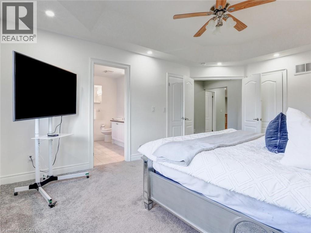 Carpeted interior space featuring recessed lighting, a ceiling fan with wood-finish blades, and white paneled doors - 584 Pinery Trail, Waterloo, ON - Indoor Photo Showing Bedroom
