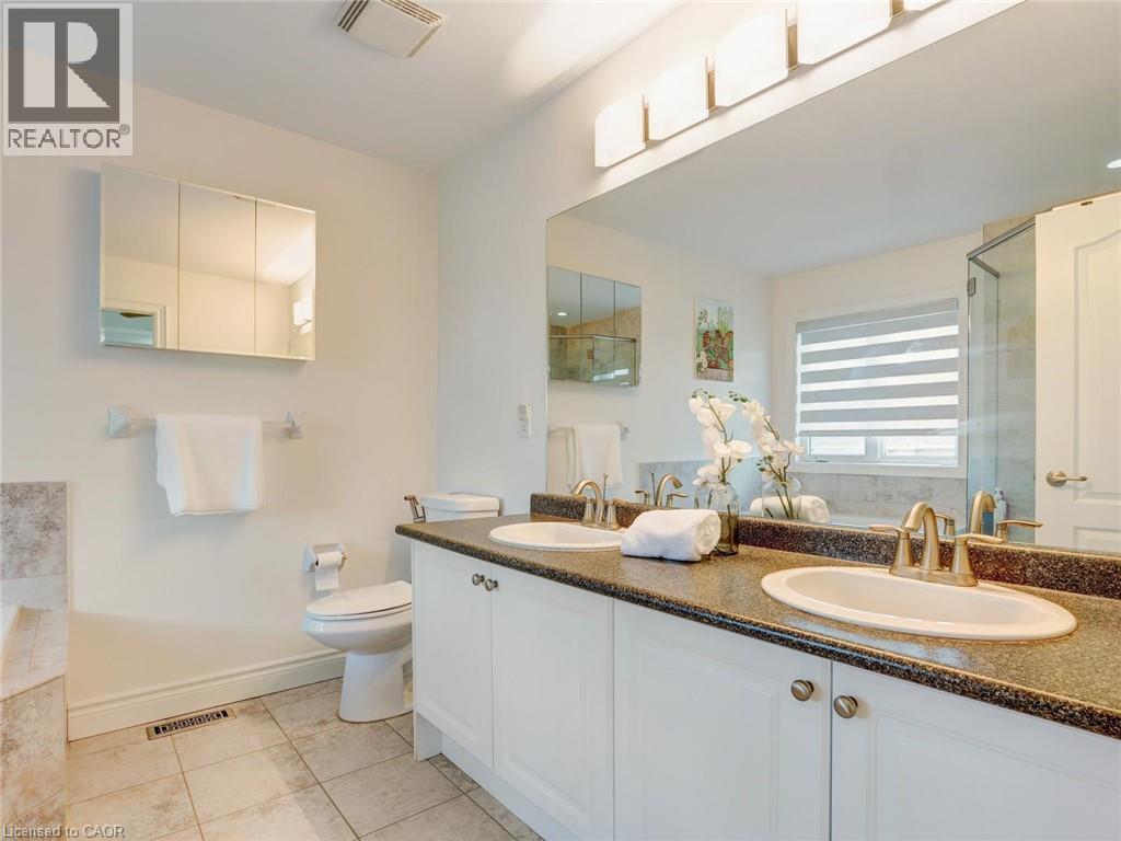 Double vanity with individual sinks, granite-finish countertop, and gold-tone fixtures - 584 Pinery Trail, Waterloo, ON - Indoor Photo Showing Bathroom