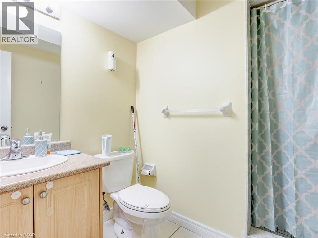 Bathroom featuring a light wood-finish vanity with an integrated sink, a speckled countertop, and a vanity mirror with overhead lighting - 584 Pinery Trail, Waterloo, ON - Indoor Photo Showing Bathroom