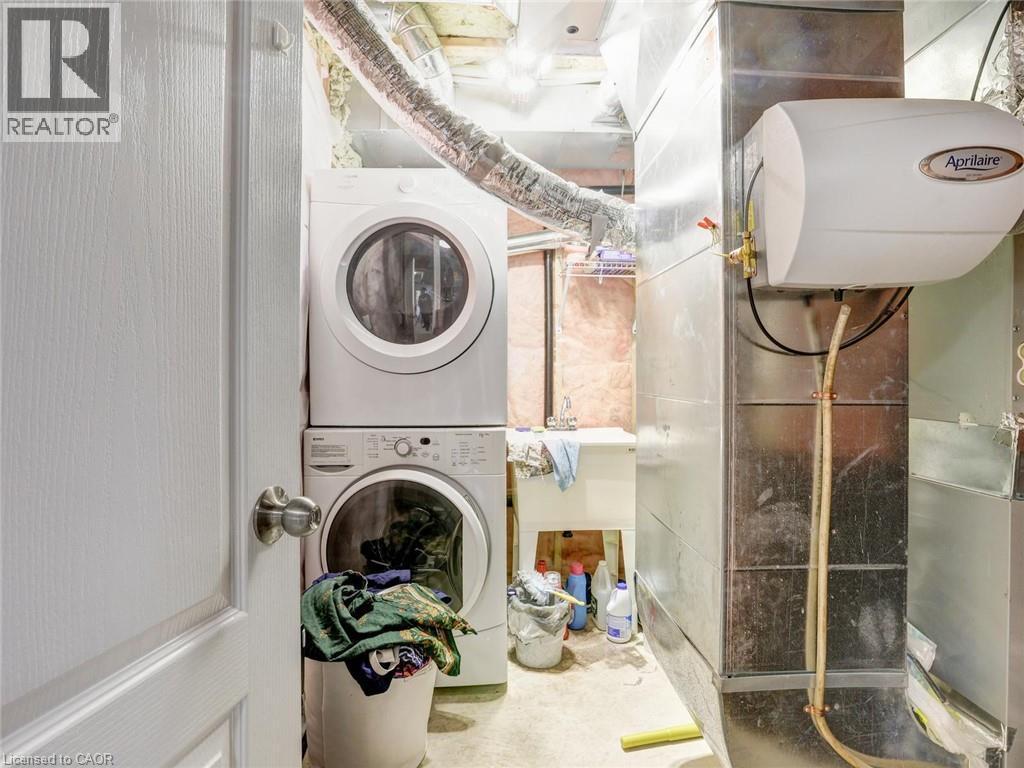 Dedicated laundry area featuring a stacked washer and dryer, utility sink, and visible ductwork - 584 Pinery Trail, Waterloo, ON - Indoor Photo Showing Laundry Room