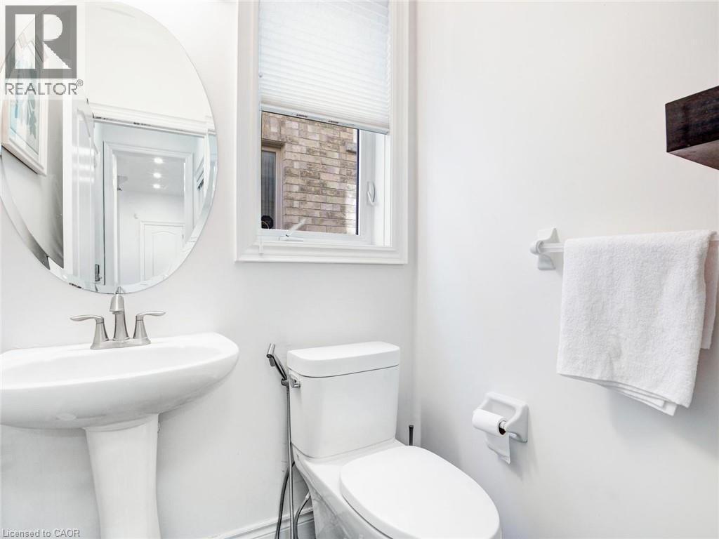 Pedestal sink with brushed nickel faucet, oval wall mirror, and privacy window with pleated blinds - 584 Pinery Trail, Waterloo, ON - Indoor Photo Showing Bathroom