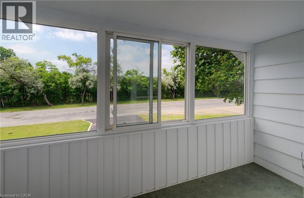 Enclosed sunroom featuring multiple windows, a sliding glass panel, white vertical paneling, and white horizontal siding - 182 Avalon Place, Kitchener, ON - Photo Showing Other Room