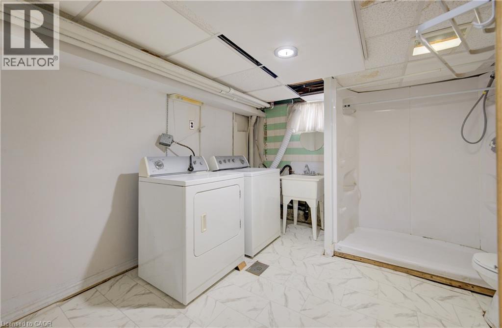 Utility area with white appliances, a freestanding basin sink, and a shower stall - 182 Avalon Place, Kitchener, ON - Indoor Photo Showing Laundry Room