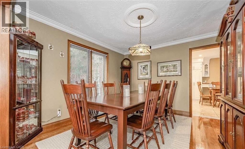 Elegant formal dining room showcasing rich wood-finish flooring, a substantial wood dining table with matching chairs, and classic wood cabinetry with glass-front display doors - 28 Walnut Drive, Guelph, ON - Indoor Photo Showing Dining Room