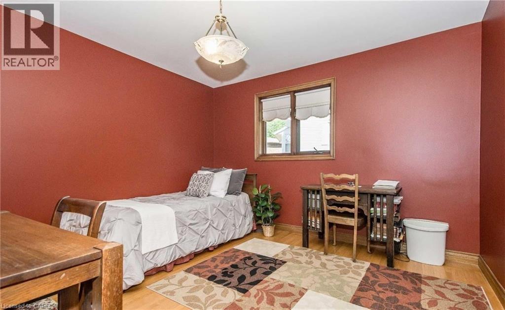 Bright bedroom showcasing warm coral walls, wood-finish flooring, and a large casement window with natural light - 28 Walnut Drive, Guelph, ON - Indoor Photo Showing Bedroom