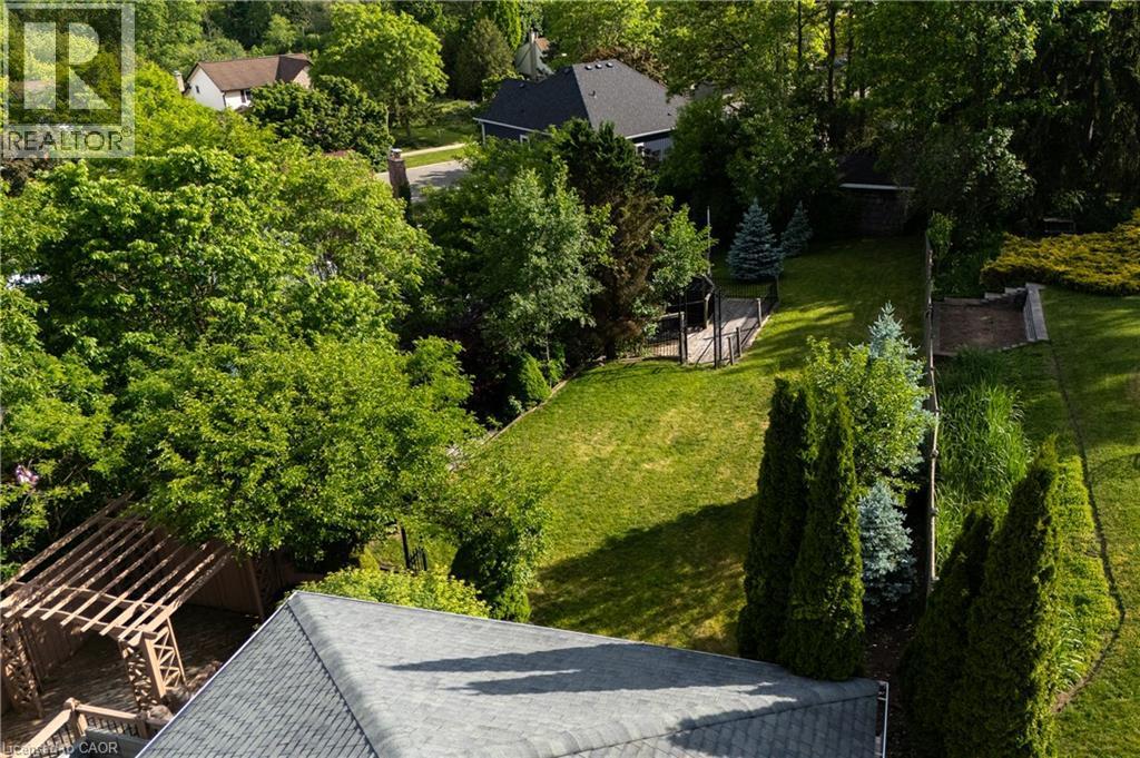 Expansive rear yard featuring a manicured lawn, established landscaping, a wooden pergola, and a visible storage shed - 907 Doon Village Road, Kitchener, ON - Outdoor