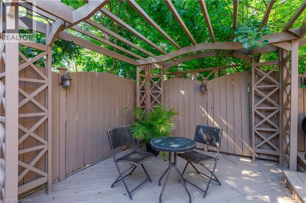 Covered patio retreat featuring a sturdy wood-beam pergola with lattice-paneled walls and integrated sconce lighting - 907 Doon Village Road, Kitchener, ON - Outdoor With Deck Patio Veranda With Exterior