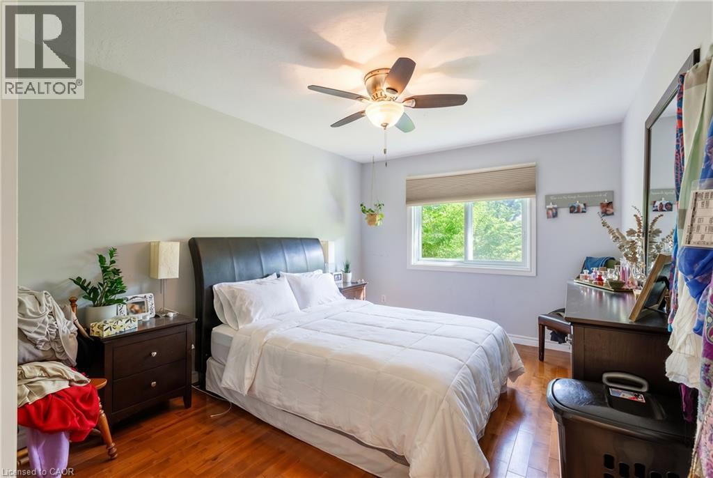Bright bedroom featuring hardwood flooring, a ceiling fan with integrated lighting, and dark wood furnishings - 907 Doon Village Road, Kitchener, ON - Indoor Photo Showing Bedroom