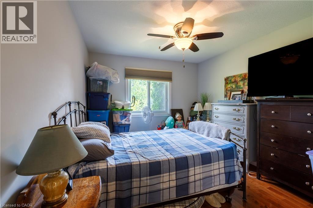 Bright bedroom featuring hardwood flooring, ceiling fan with integrated lighting, and ample natural light from sliding glass doors - 907 Doon Village Road, Kitchener, ON - Indoor Photo Showing Bedroom
