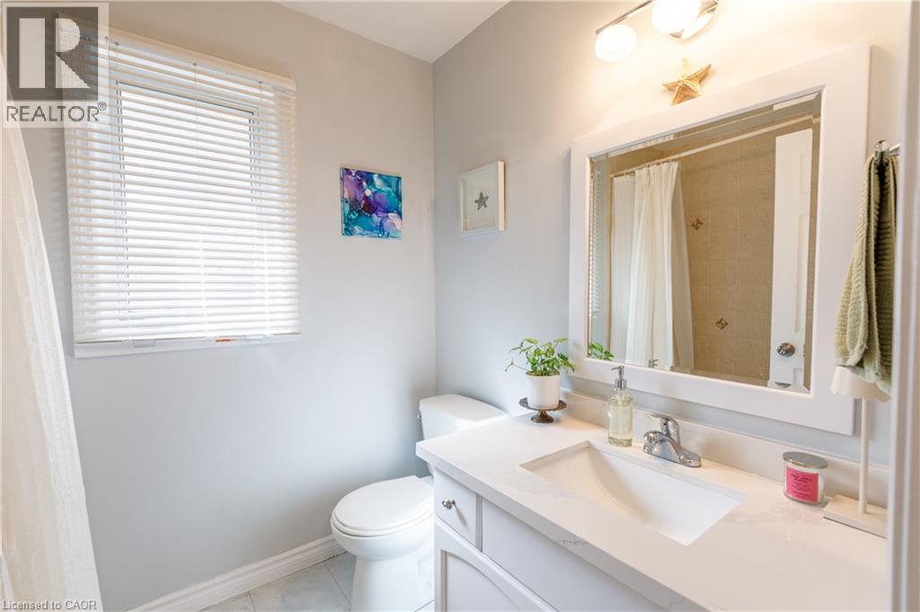 Bathroom featuring a single vanity with an integrated rectangular sink, a light-toned countertop, and a chrome faucet - 907 Doon Village Road, Kitchener, ON - Indoor Photo Showing Bathroom