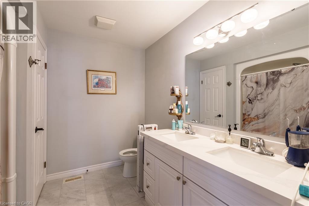 Bathroom featuring a double vanity with integrated sinks, a large wall-mounted mirror, and a wall-mounted light fixture - 907 Doon Village Road, Kitchener, ON - Indoor Photo Showing Bathroom
