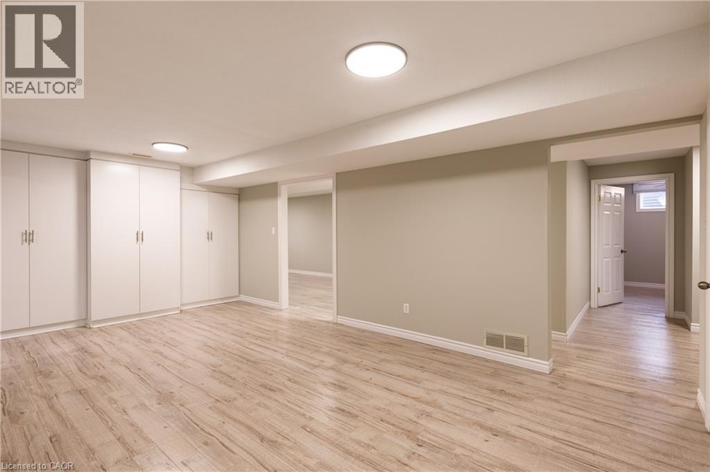 Spacious room featuring wood-finish flooring, extensive built-in white cabinetry, recessed lighting, neutral wall paint, and white trim - 907 Doon Village Road, Kitchener, ON - Indoor
