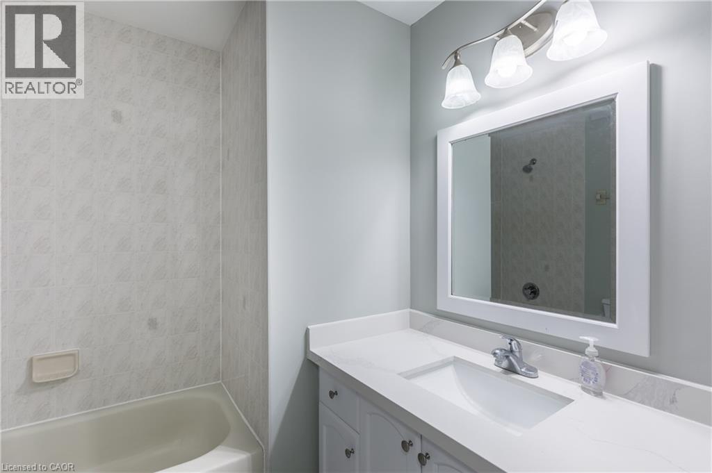 Contemporary bathroom featuring a framed mirror with integrated lighting, white quartz countertop with rectangular undermount sink, gray cabinetry with hardware accents, chrome faucet fixture, and adj - 907 Doon Village Road, Kitchener, ON - Indoor Photo Showing Bathroom