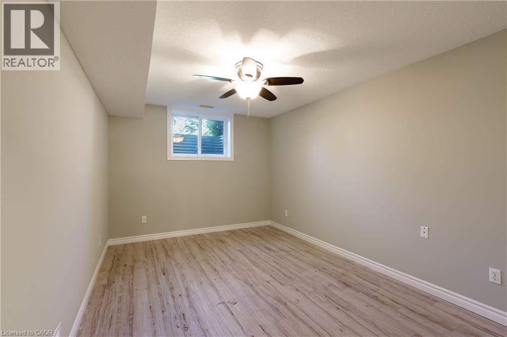 Bright and spacious bedroom featuring wood-finish flooring, neutral wall finishes, and a ceiling fan with integrated lighting - 907 Doon Village Road, Kitchener, ON - Indoor Photo Showing Other Room