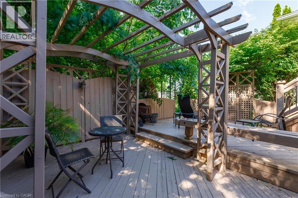 Sophisticated outdoor entertaining space featuring a custom wood pergola with geometric lattice detailing, composite decking, and integrated seating areas - 907 Doon Village Road, Kitchener, ON - Outdoor With Deck Patio Veranda With Exterior