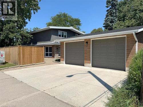 Exterior featuring a two-car garage with three panel doors, brick and stone accents, and dark siding - 69 Pleasant Avenue, Hamilton, ON - Outdoor