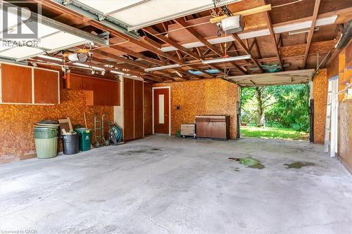 Two-car garage featuring a concrete floor, exposed wooden beams, built-in cabinetry, and three overhead garage doors opener system - 69 Pleasant Avenue, Hamilton, ON - Indoor Photo Showing Other Room