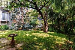 Landscaped rear yard featuring mature trees and a manicured lawn - 