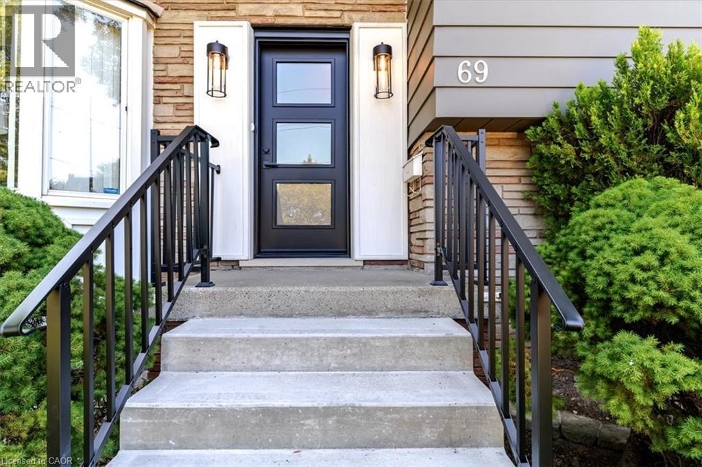 Welcoming entry featuring a concrete staircase with black metal railings leading to a dark-finish entry door with multi-pane glass panels - 69 Pleasant Avenue, Hamilton, ON - Outdoor With Exterior