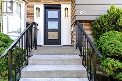 Welcoming entry featuring a concrete staircase with black metal railings leading to a dark-finish entry door with multi-pane glass panels - 