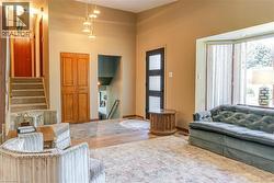 Multi-level entryway featuring a contemporary front door with frosted glass panels, a bay window, and a grand staircase with carpeted treads - 