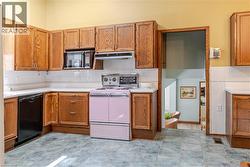 Kitchen featuring wood cabinetry, white countertops, white subway tile backsplash, and a pink range - 