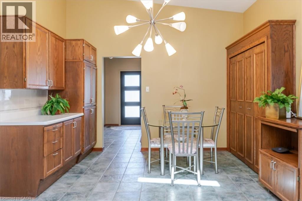Dining area featuring a modern Sputnik-style chandelier, tile flooring, and a built-in wood-finish cabinet with bi-fold doors - 69 Pleasant Avenue, Hamilton, ON - Indoor Photo Showing Dining Room