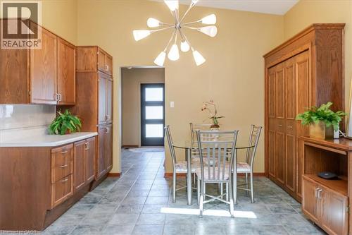 Dining area featuring a modern Sputnik-style chandelier, tile flooring, and a built-in wood-finish cabinet with bi-fold doors - 69 Pleasant Avenue, Hamilton, ON - Indoor Photo Showing Dining Room