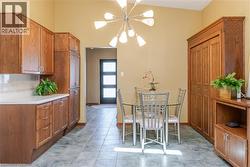 Dining area featuring a modern Sputnik-style chandelier, tile flooring, and a built-in wood-finish cabinet with bi-fold doors - 