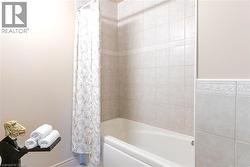 White bathtub with tile surround, featuring decorative accent tiles and a patterned shower curtain - 