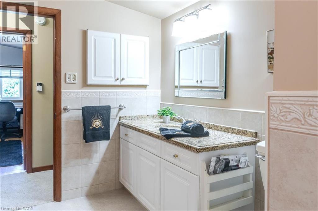 Elegant primary bathroom featuring a white vanity with granite countertop, recessed medicine cabinet with mirror, and subway tile backsplash - 69 Pleasant Avenue, Hamilton, ON - Indoor
