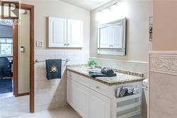 Elegant primary bathroom featuring a white vanity with granite countertop, recessed medicine cabinet with mirror, and subway tile backsplash - 
