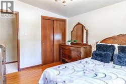 Bedroom featuring wood-finish flooring, light-colored walls, and a ceiling-mounted light fixture - 