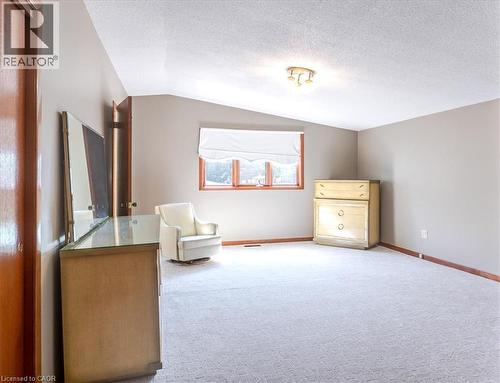 Spacious upper-level room with neutral carpet flooring, angled ceiling with recessed lighting, and large picture window with wood trim framing natural light - 69 Pleasant Avenue, Hamilton, ON - Indoor
