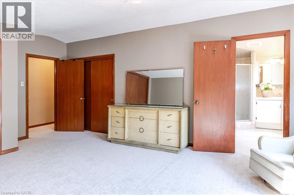 Spacious carpeted room featuring multiple wood-paneled doors, neutral wall tones, and recessed lighting - 69 Pleasant Avenue, Hamilton, ON - Indoor