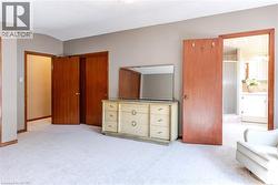 Spacious carpeted room featuring multiple wood-paneled doors, neutral wall tones, and recessed lighting - 
