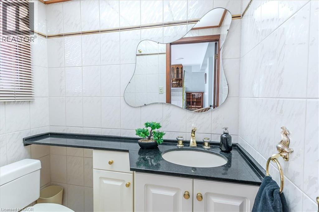 2 Piece Bathroom featuring a white tile surround, dark countertop with an integrated sink, and white cabinetry - 69 Pleasant Avenue, Hamilton, ON - Indoor Photo Showing Bathroom
