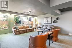 Lower level Recreation Room featuring expansive window wall, light-colored carpeting, recessed lighting, and wall-mounted light fixtures - 