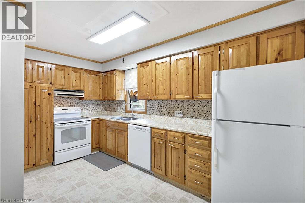 Kitchen featuring extensive natural wood cabinetry, light-toned countertops, and a patterned backsplash - 371 Ottawa Street S, Kitchener, ON - Indoor Photo Showing Kitchen With Double Sink