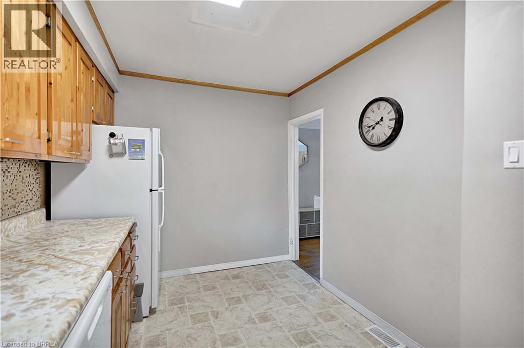 Kitchen featuring wood cabinetry with polished hardware, light-toned patterned countertops, and a mosaic tile backsplash - 371 Ottawa Street S, Kitchener, ON -