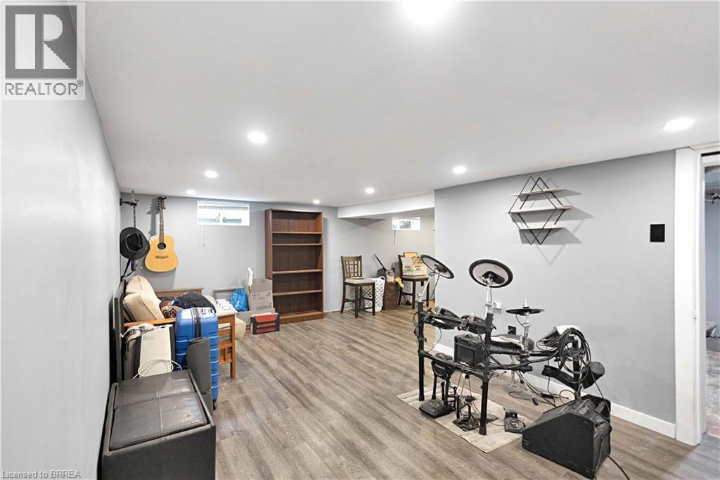 Spacious room featuring wood-finish flooring, recessed lighting, neutral painted walls, a built-in bookshelf, and a window providing natural light - 371 Ottawa Street S, Kitchener, ON - Indoor Photo Showing Laundry Room