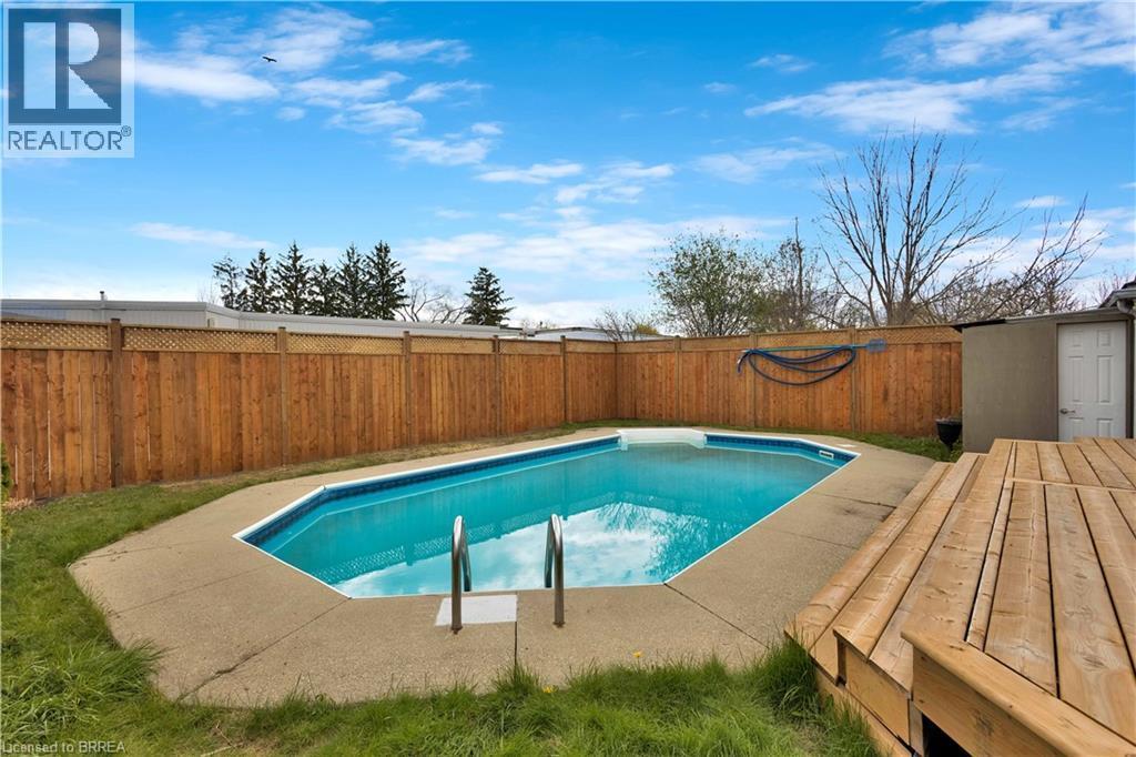 Backyard featuring an in-ground pool with concrete surround, a multi-level wood deck, and a wood privacy fence with lattice detailing - 371 Ottawa Street S, Kitchener, ON - Outdoor With In Ground Pool With Backyard