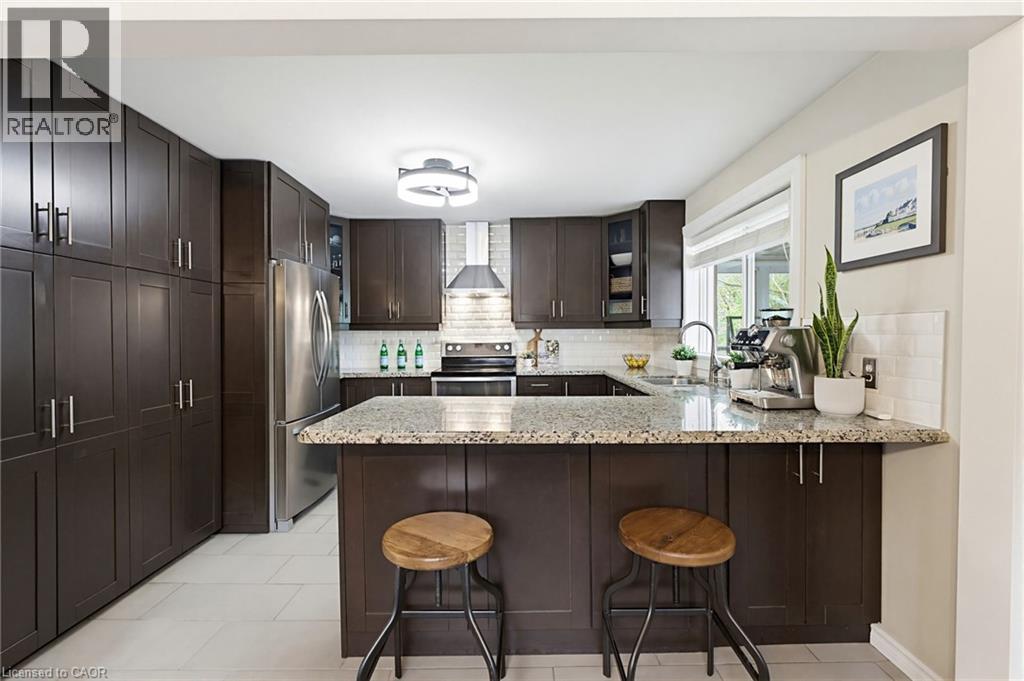 Kitchen featuring dark wood-finish cabinetry, light speckled countertops, a stainless steel refrigerator, and a tiled backsplash - 60 Avenue Road, Cambridge, ON - Indoor Photo Showing Kitchen With Upgraded Kitchen
