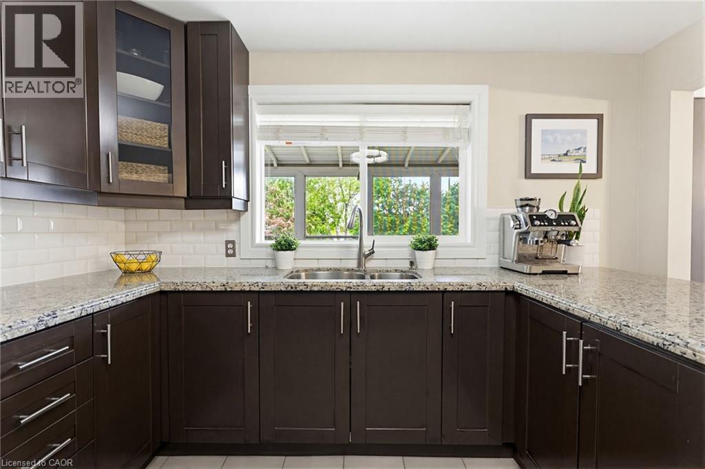 U-shaped kitchen with dark wood cabinetry, light speckled countertops, white subway tile backsplash, and a double basin stainless steel sink - 60 Avenue Road, Cambridge, ON - Indoor Photo Showing Kitchen With Double Sink With Upgraded Kitchen