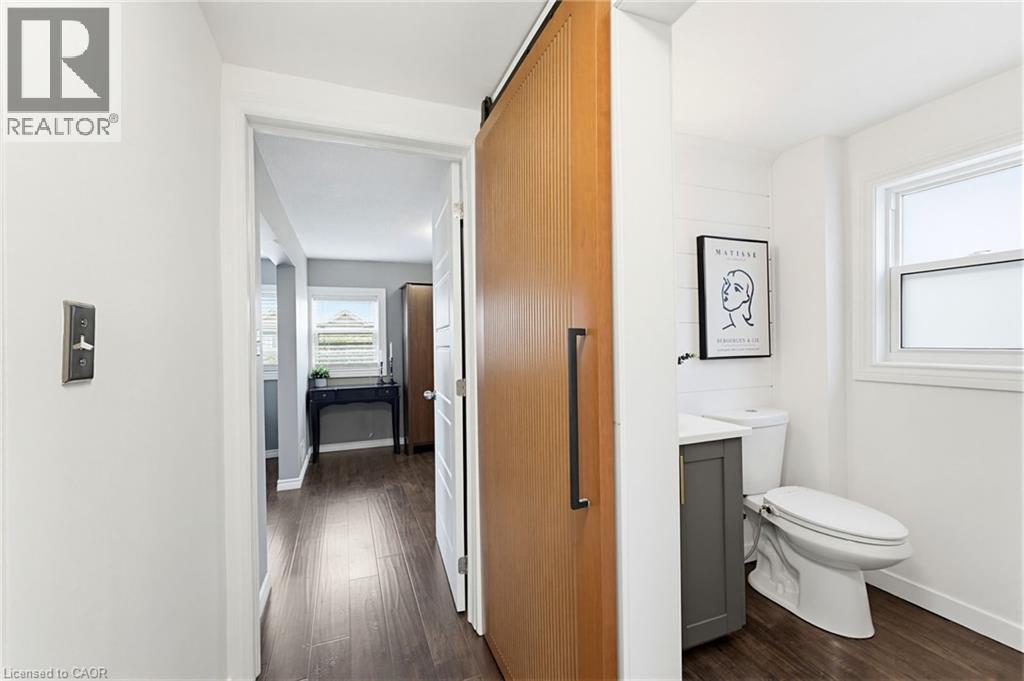 Sliding wood-finish barn door with matte black hardware - 60 Avenue Road, Cambridge, ON - Indoor Photo Showing Bathroom