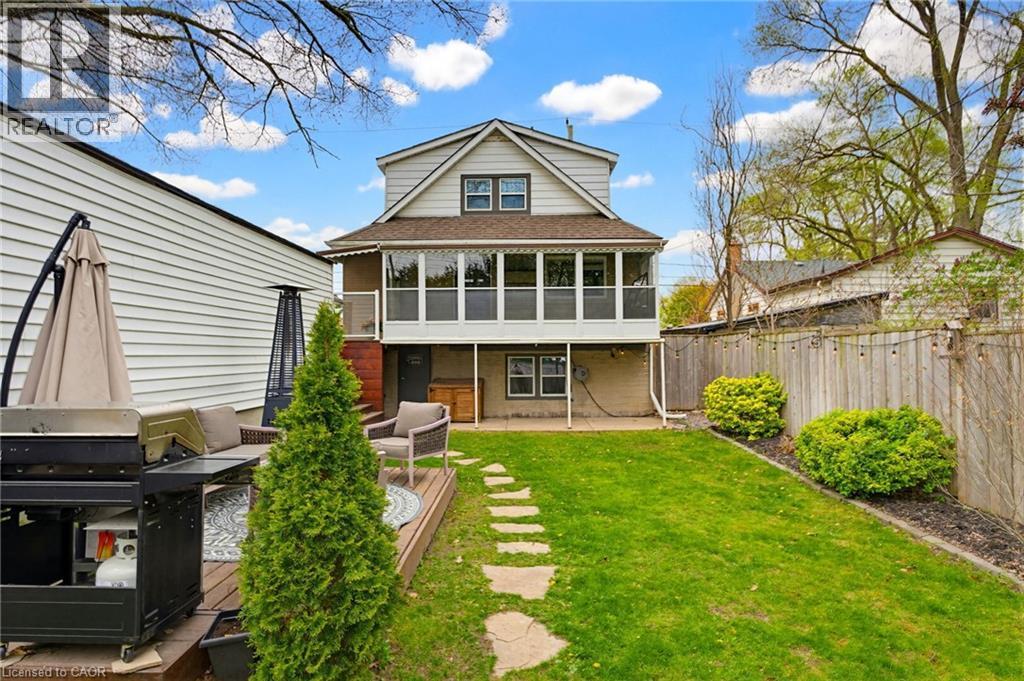 Rear exterior with an upper-level enclosed porch, ground-level patio, and a stone-path leading to a private backyard - 60 Avenue Road, Cambridge, ON - Outdoor