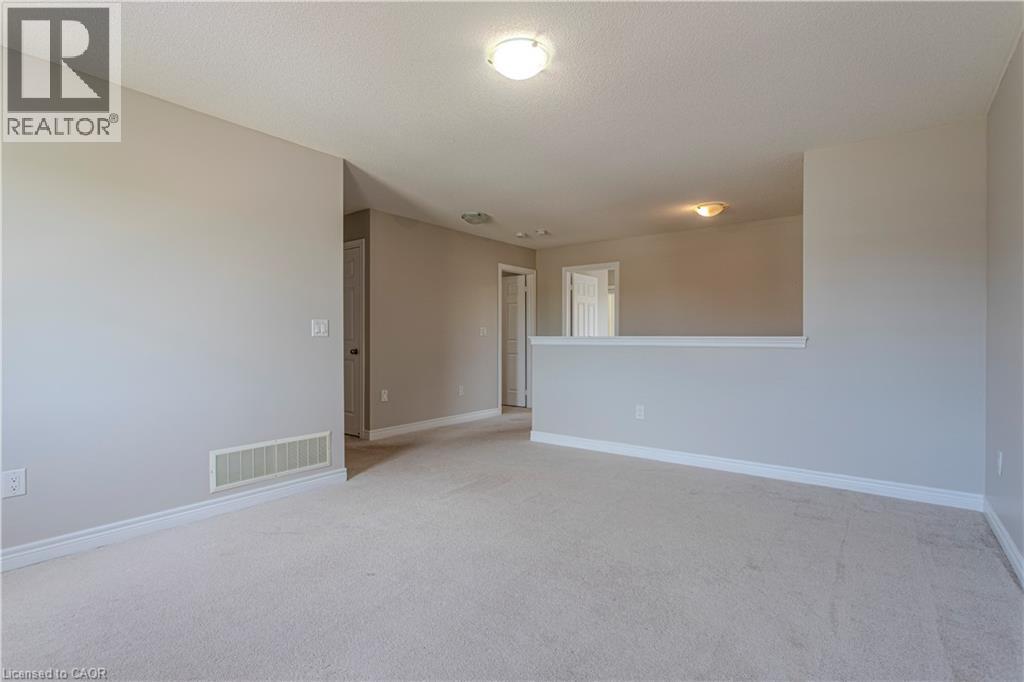 Spacious carpeted room featuring light gray walls, white baseboards, and a semi-flush mount ceiling light - 3896 Tufgar Crescent, Burlington, ON - Indoor Photo Showing Other Room